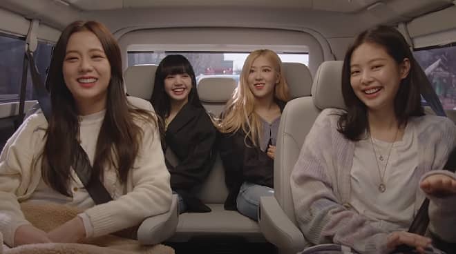 screencap from BLACKPINK: light up the sky documentary with the 4group members sitting in a car facing the camera and laughing